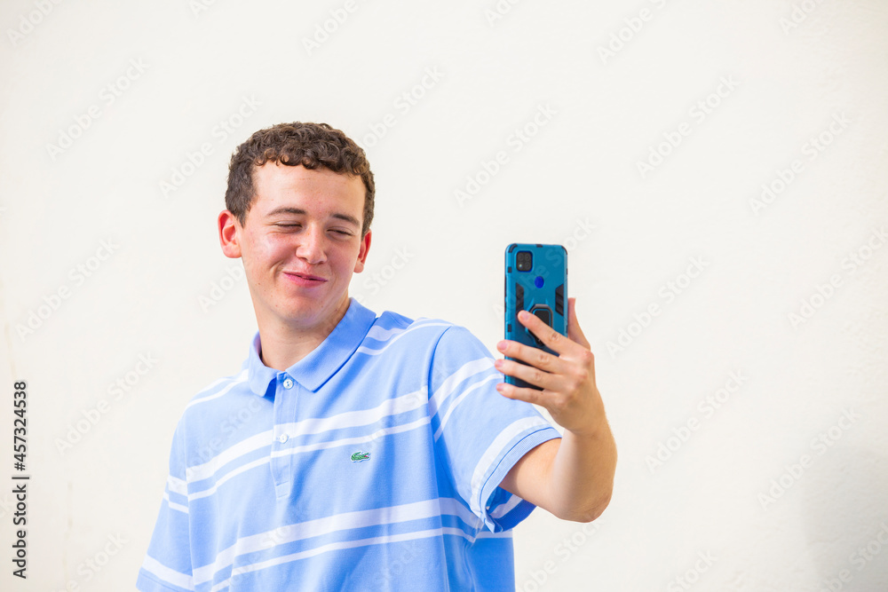 chico joven sonriente hablando en una videoconferencia con telefono movil aislado fondo amarillo
