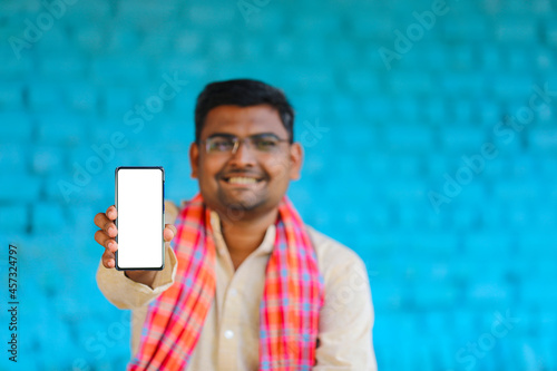 technology concept : Young indian farmer showing smartphone at his home photo