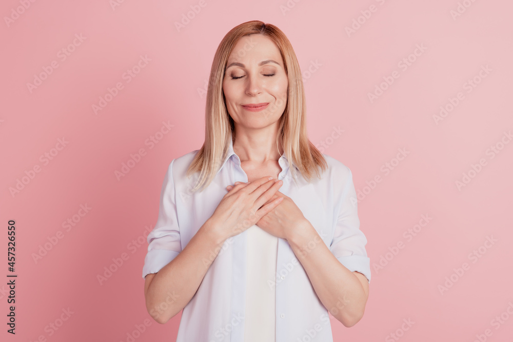 Portrairt of lovely young woman close eyes hands palms on chest grateful isolated over pink background Portrairt of lovely young woman close eyes hands palms on chest grateful isolated over pink background