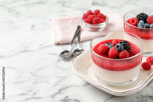 Foto Delicious panna cotta with fruit coulis and fresh berries served on white marble table