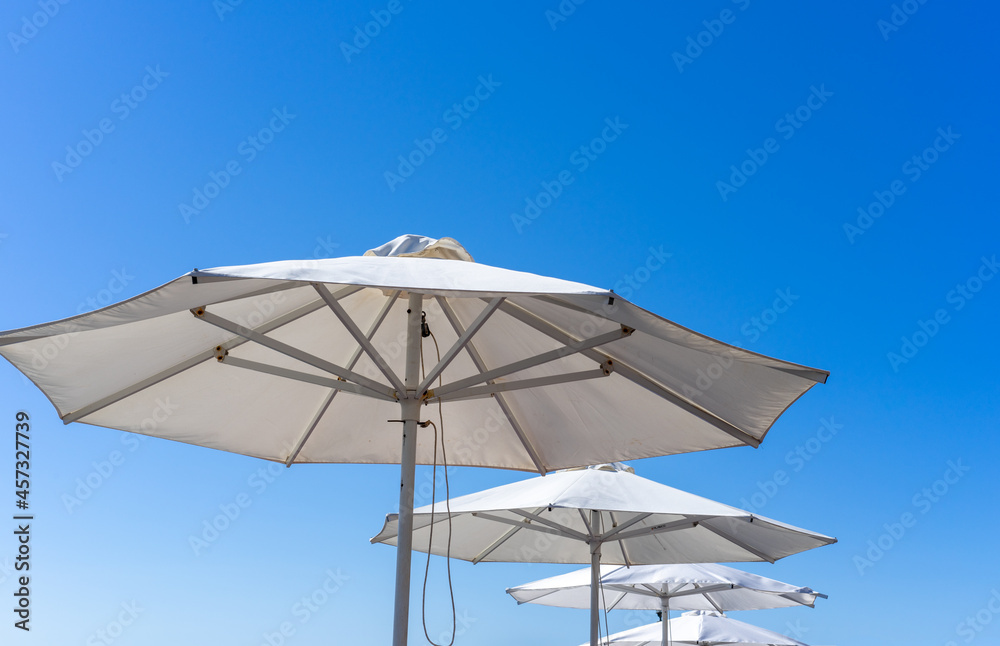 White parasols. Many white beach umbrellas under the blue sky.