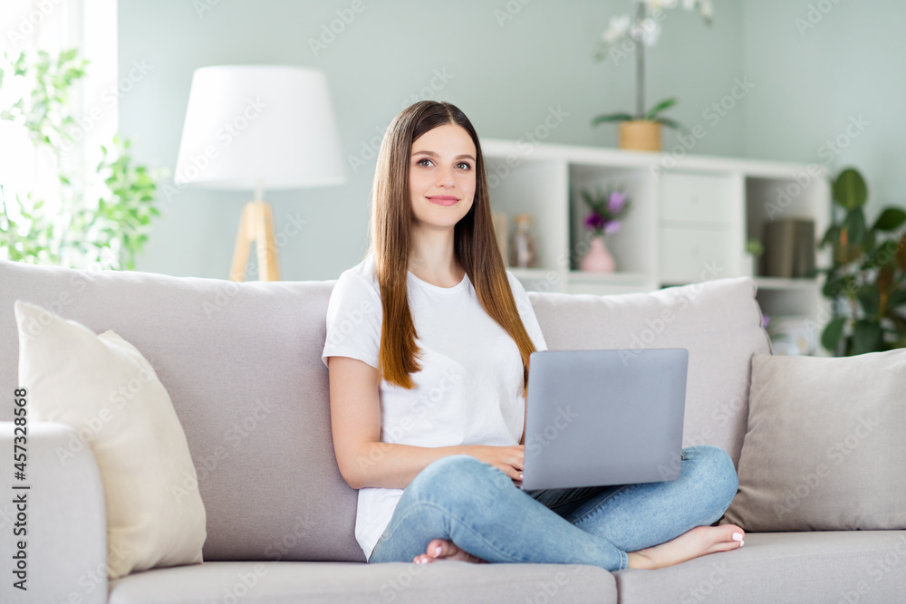 Portrait of attractive skilled girl sitting on divan using laptop study learn education at home living room indoors Portrait of attractive skilled girl sitting on divan using laptop study learn education at home living room indoors