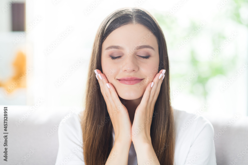 Portrait of attractive dreamy peaceful brown-haired girl touching smooth face enjoying at home indoors Portrait of attractive dreamy peaceful brown-haired girl touching smooth face enjoying at home indoors