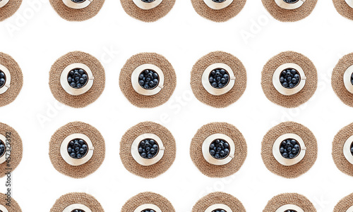 Seamless pattern with blueberries in a cup and on a saucer and jute napkin and texture background, flat lay.