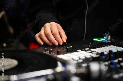 Disc jockey mixes music with cross fader knob on sound mixer device. Professional hip hop dj playing musical tracks on party with turntables and modern mixing controller