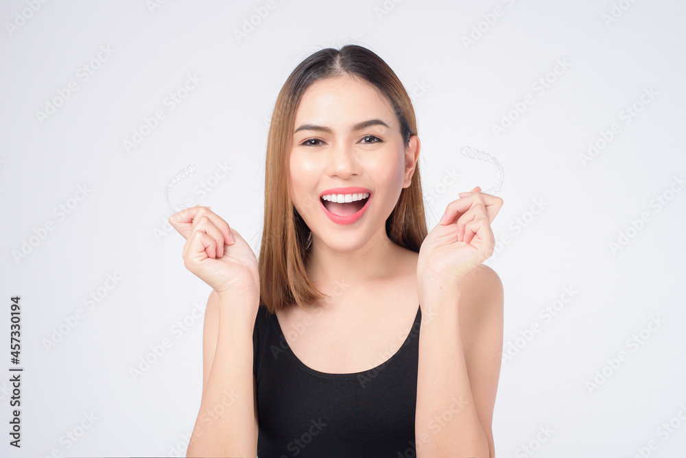 Young smiling woman holding invisalign braces in studio, dental healthcare and Orthodontic concept Young smiling woman holding invisalign braces in studio, dental healthcare and Orthodontic concept