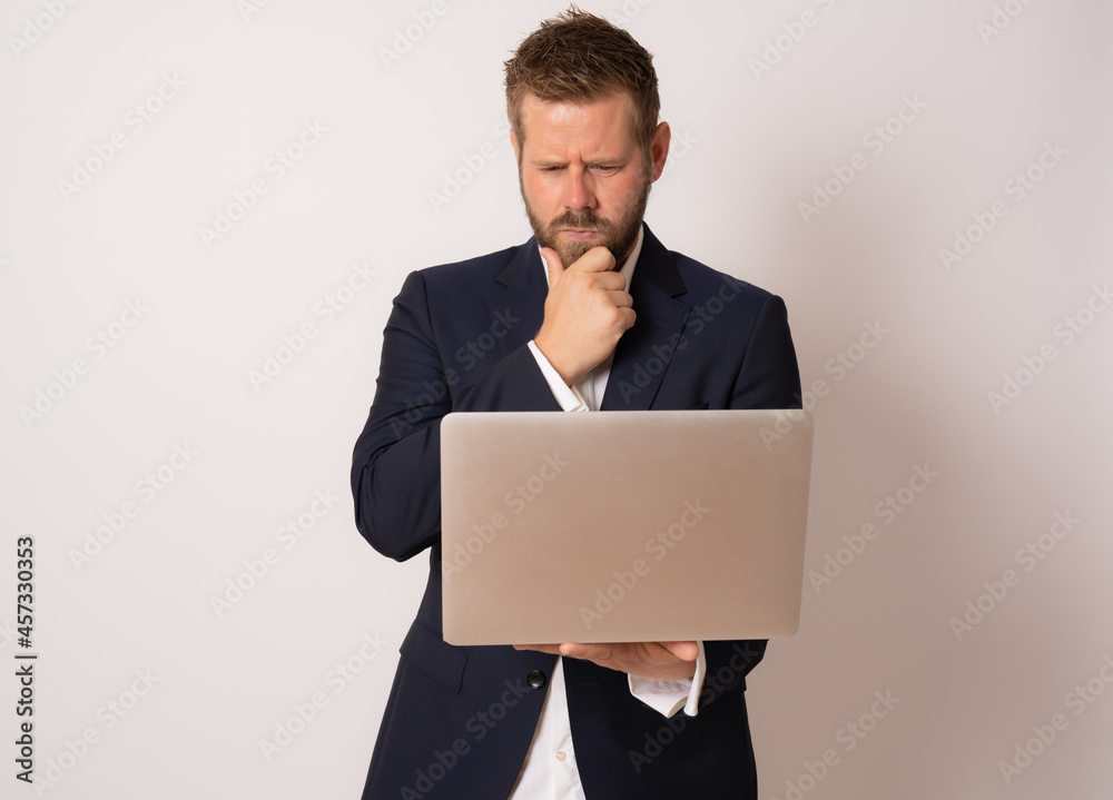 Young business man standing with laptop. Handsome guy holding open notebook in his hand and work on it. Information, technology concept. Young business man standing with laptop. Handsome guy holding open notebook in his hand and work on it. Information, technology concept.