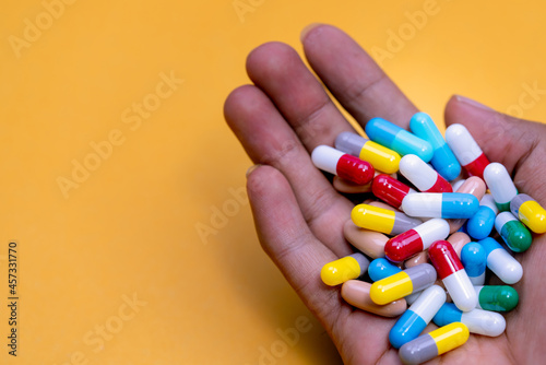 Man hand holding colorful capsule pills on yellow background. Prescription drugs. Drug overuse and polypharmacy concept. Drug allergy. Pharmaceutical industry. Pharmacy banner. Healthcare and medicine photo