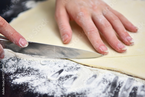 girl cuts the dough with a knife on the croissant baking table at home