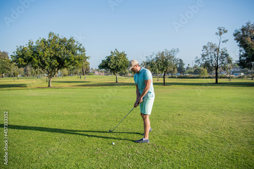 portrait of golfer in cap with golf club. people lifestyle. man playing game on green grass.