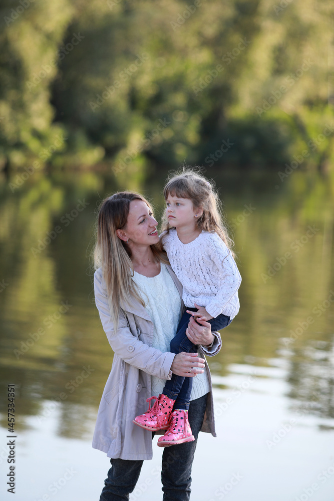 Mother and daughter walk in park near river. Mother and daughter walk in park near river.