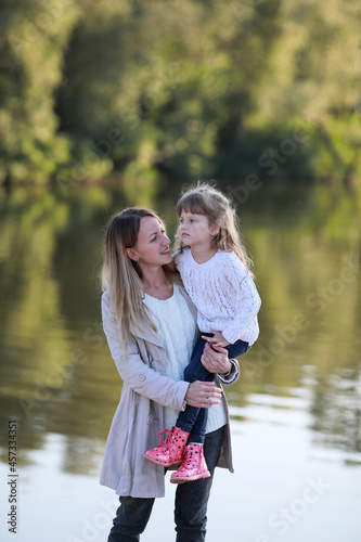 Mother and daughter walk in park near river. © Stanislav