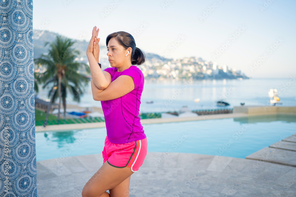 Woman practices yoga in front of the pool. Yoga poses outdoors