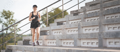 A healthy adult Asian woman running up on concrete stairs of the city stadium to strengthen body