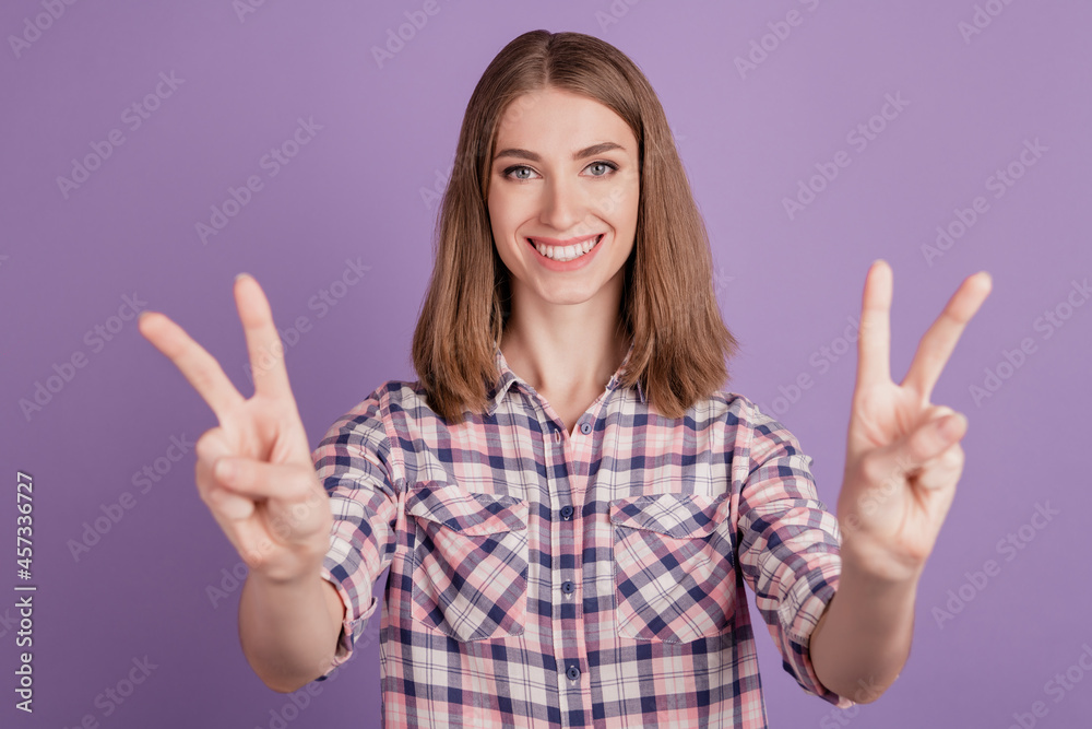 Photo of young cheerful girl happy positive smile show peace cool v-sign isolated over violet color background