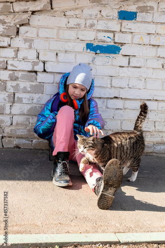 Teenage girl strokes cat the street. Concept of love for animals and environmental protection.