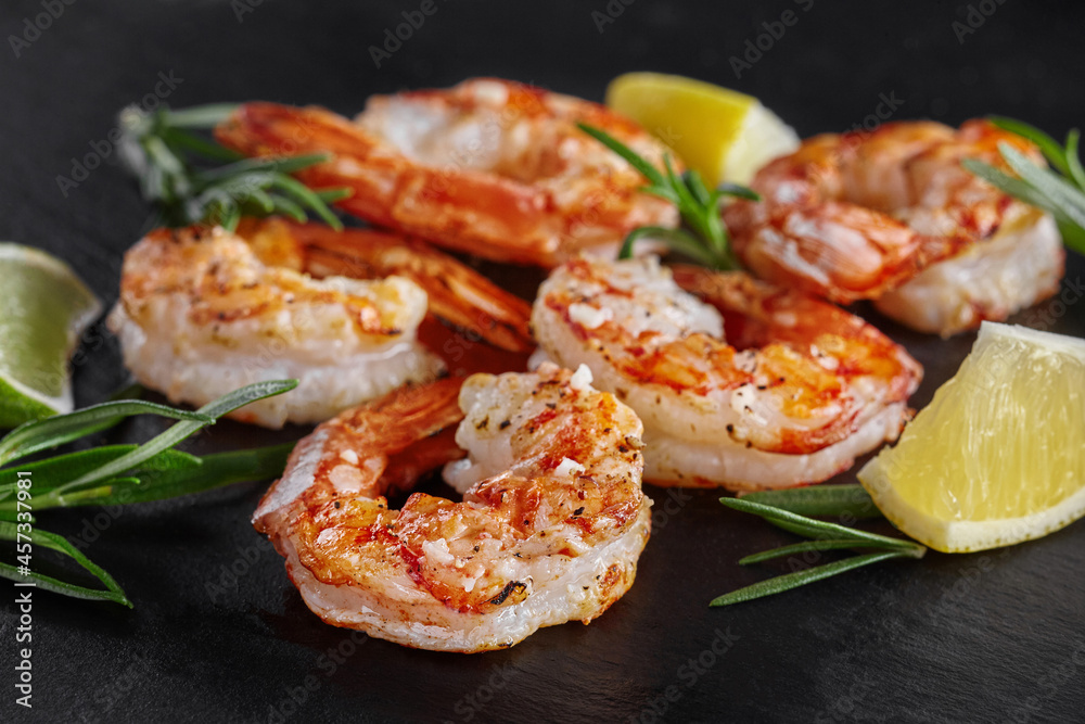 Fried scampi tails with lime, lemon and rosemary on black background Fried scampi tails with lime, lemon and rosemary on black background