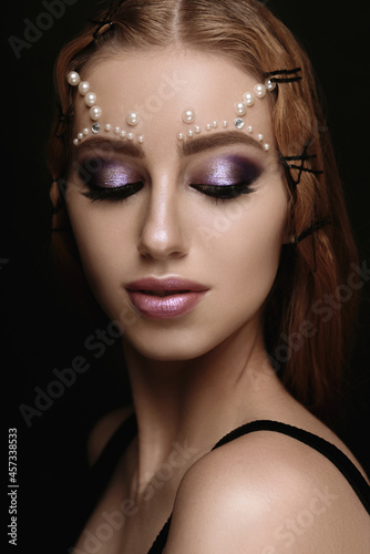 Beautiful woman portrait with art make up, pearl beads on face.
