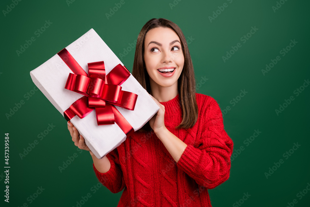 Photo of young excited girl happy positive smile curious shake present box christmas isolated over green color background Photo of young excited girl happy positive smile curious shake present box christmas isolated over green color background