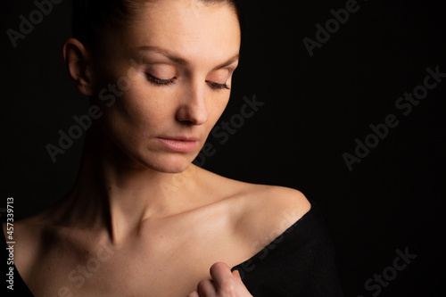 portrait of a girl on a black background with open shoulders straighte