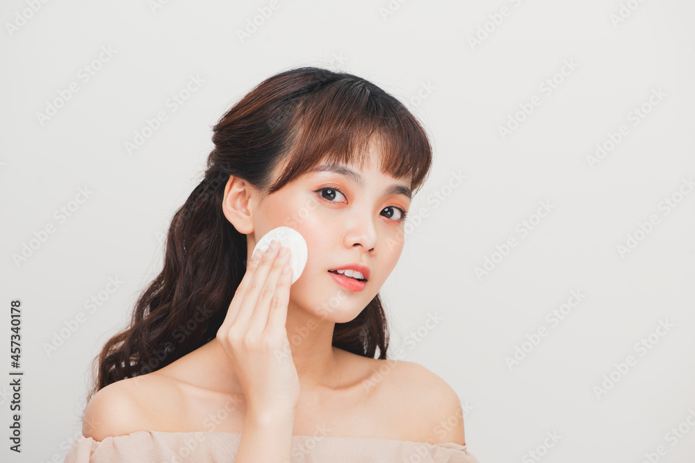 Asian teenager girl cleaning her face with a lotion and a cotton pad Asian teenager girl cleaning her face with a lotion and a cotton pad
