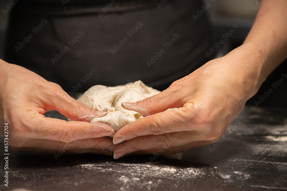 close-up of female hands kneading dough for making artisan bread at home bakery