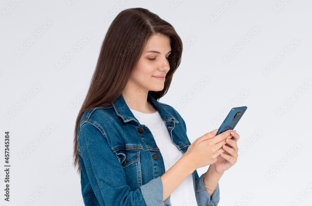 Pleased brunette woman writing message on smartphone over white background Pleased brunette woman writing message on smartphone over white background