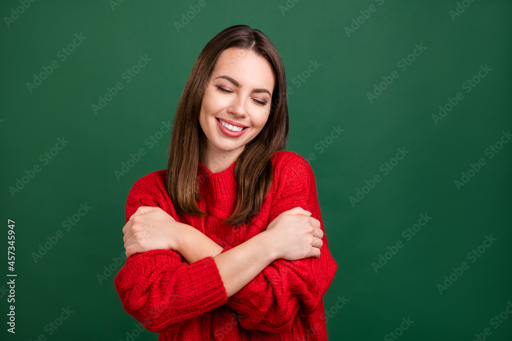Obraz premium Photo portrait girl in red pullover dreamy embracing herself smiling isolated green color background