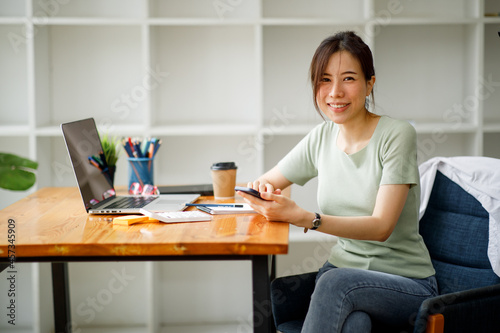 Portrait of Asian young female Businesswoman working on laptop computer doing finances,accounting analysis,report,data and pointing graph at the office.