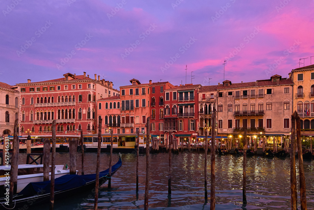 Sunset view of Grand Canal, Venice, Italy. Vaporetto or waterbus station, boats, gondolas moored by walkways, beautiful sunset clouds, UNESCO heritage