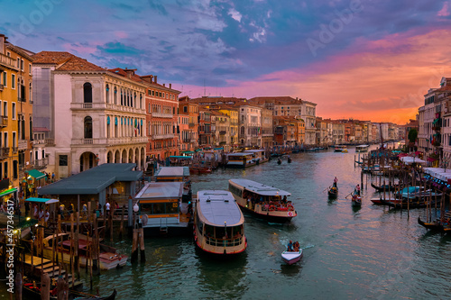 Sunset view of Grand Canal, Venice, Italy. Vaporetto or waterbus station, boats, gondolas moored by walkways, beautiful sunset clouds, UNESCO heritage