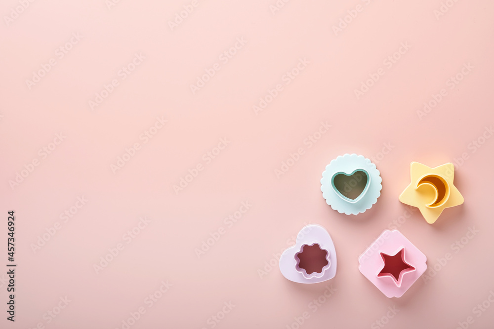 Multicolored cookie molds cutters on pink background with copy space for your advertisement and text. Baking concept. Flat lay. Mock up. Multicolored cookie molds cutters on pink background with copy space for your advertisement and text. Baking concept. Flat lay. Mock up.