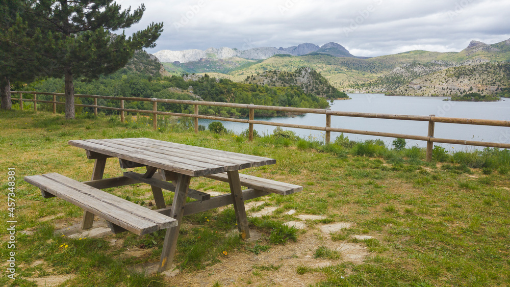 Tranquila area de descanso donde hay bancos y mesas de madera donde disfrutar de un picnic y admirar el paisaje montañoso que rodea al embalse de Barrios de Luna en la provincia de León. España. Tranquila area de descanso donde hay bancos y mesas de madera donde disfrutar de un picnic y admirar el paisaje montañoso que rodea al embalse de Barrios de Luna en la provincia de León. España.