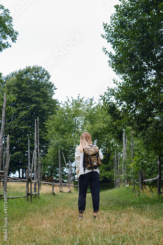 The beautiful girl traveler walks through the village. Beautiful nature landscape in countryside. Hiking journey on tourist trail. Outdoor adventure. Travel and exploration. Healthy lifestyle © Iuliia Pilipeichenko