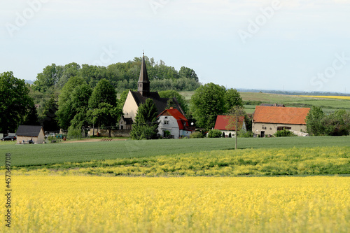 WROCLAW, POLAND - MAY 24, 2021: St. Martin Church in Gogolow at the foot of Sleza Mountain, surrounded by fields of flowering rape. photo