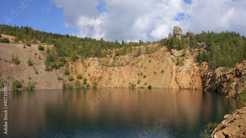 An abandoned stone quarry filled with water and trees around.