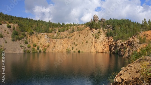 An abandoned stone quarry filled with water and trees around.