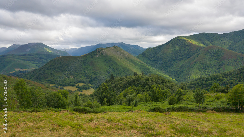 Preciosas vistas bajo las grises nubes a las verdes montañas salpicadas por los rayos del sol donde se refugia el bosque de Muniellos en Asturias, España.