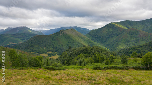 Preciosas vistas bajo las grises nubes a las verdes montañas salpicadas por los rayos del sol donde se refugia el bosque de Muniellos en Asturias, España.