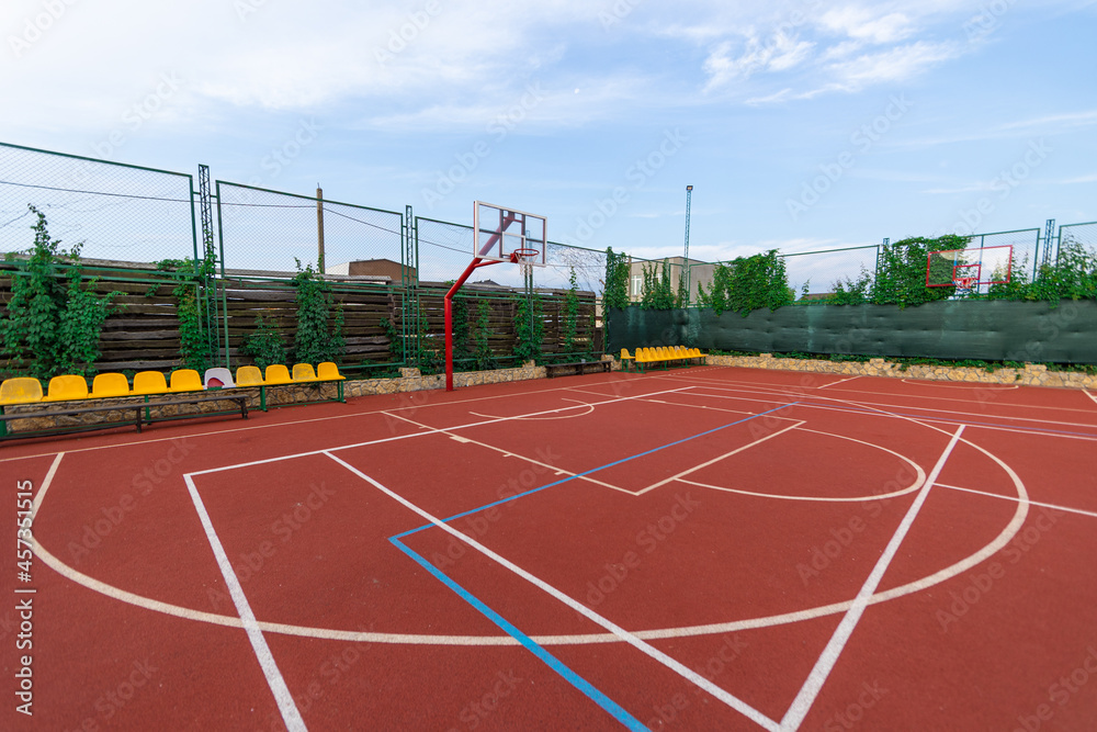 Red basketball court at day with blue sky. Sport concept
