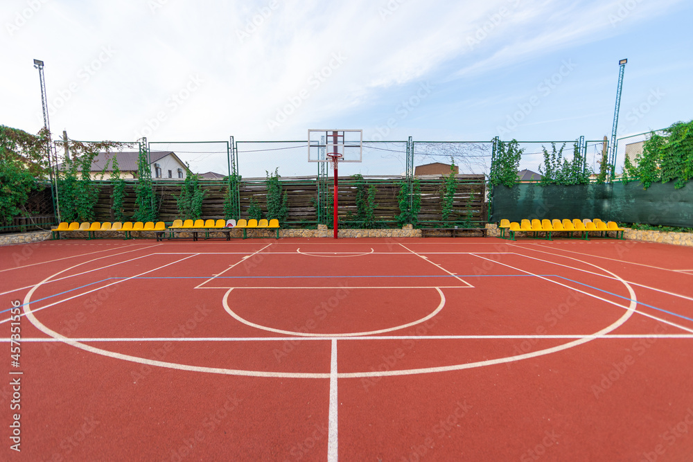 Red basketball court at day with blue sky. Sport concept