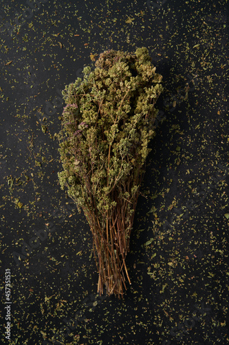 Bunch of oregano on black background. Surrounded by grated oregano.