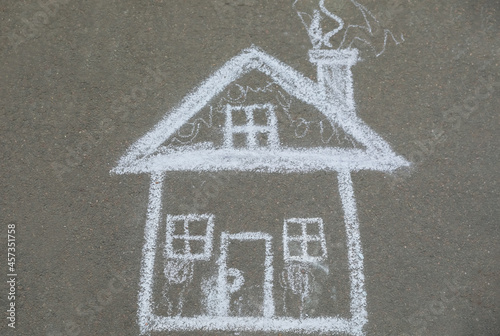 Child's chalk drawing of house on asphalt, top view