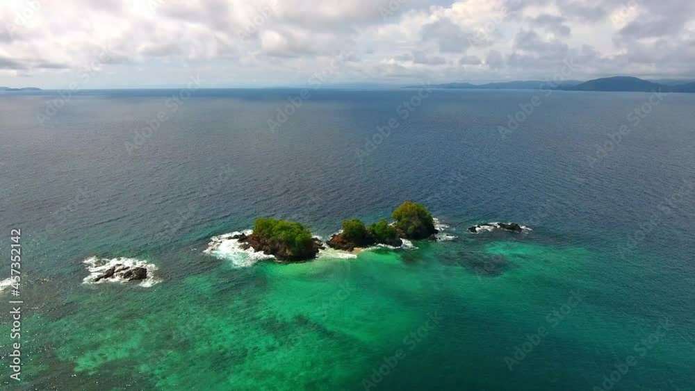 Rising Aerial View Over Small Coral Islands with Clear Water and Surrounding Waves Rising Aerial View Over Small Coral Islands with Clear Water and Surrounding Waves