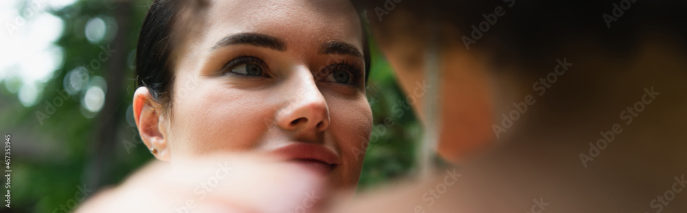 Fototapeta premium Young woman looking at blurred african american girlfriend outdoors, banner.