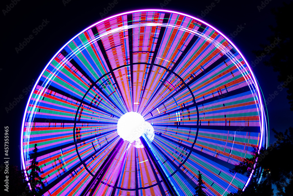 A blurry abstract Ferris wheel in an amusement park in the evening in the dark, a photo on a long shutter speed