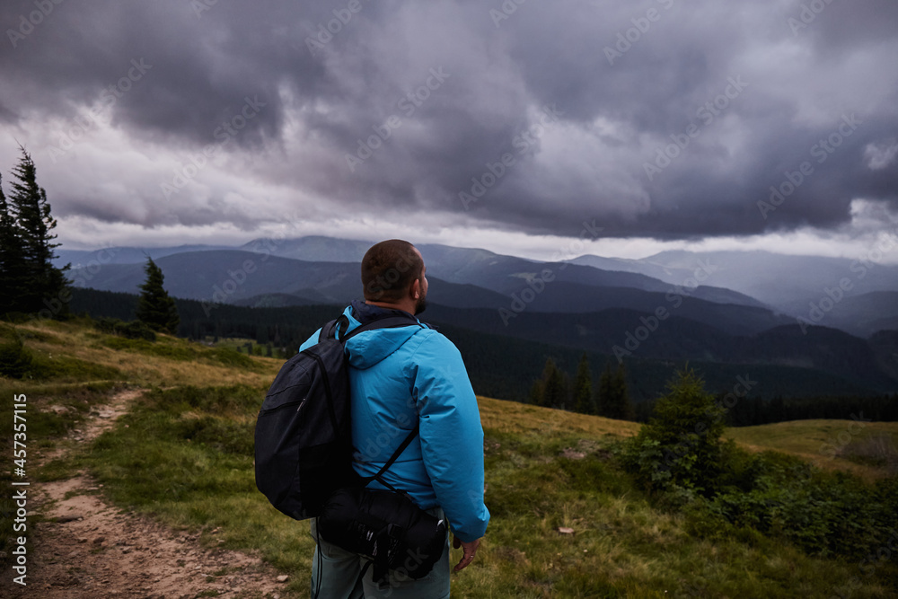 A hiker standing on a mountain meadow. Enjoying view before the storm. Hiking in Carpathian Mountains