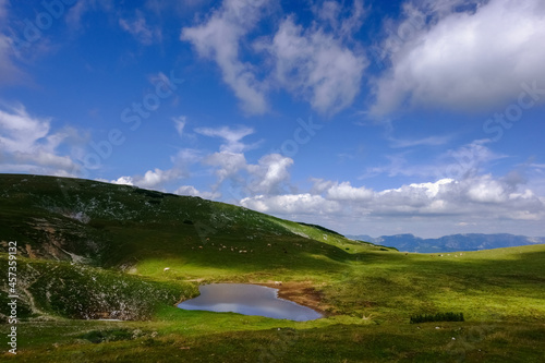 little wonderful pond in the green mountain landscape with blue sky