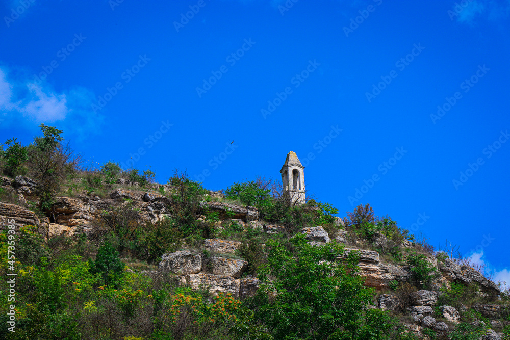 The Tower of the Winds on a rocky hill. A tall building on the top of a hill with large stones against the blue sky. The Tower of the Winds on a rocky hill. A tall building on the top of a hill with large stones against the blue sky.
