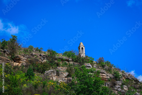 The Tower of the Winds on a rocky hill. A tall building on the top of a hill with large stones against the blue sky.